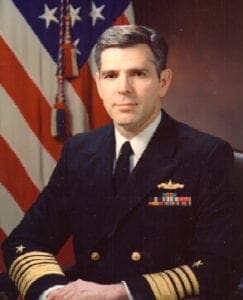 A man in military uniform sitting next to an american flag.